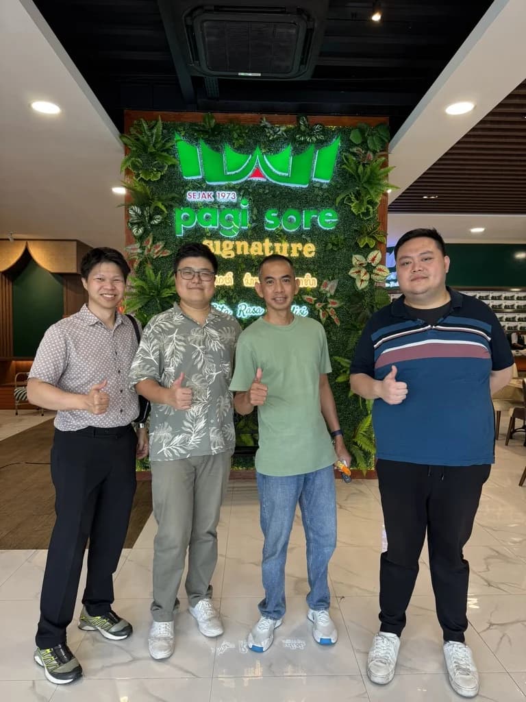 Four members of the Bali team standing in front of a green signage wall