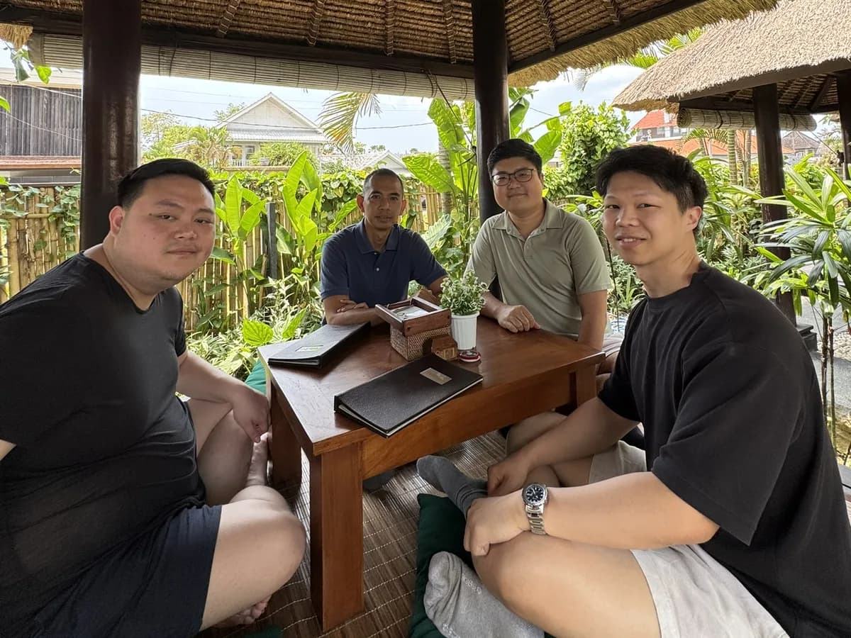 Four people working around a low table in a garden pavilion